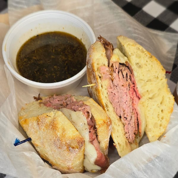 A French dip sandwich with thinly sliced roast beef and melted cheese, served with au jus.