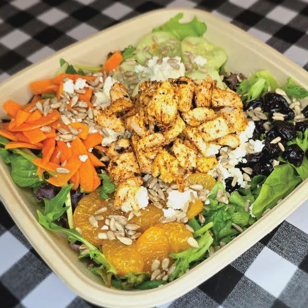 A Main St. Deli salad with chicken, mixed greens, carrots, cucumbers, oranges, and dried fruit.