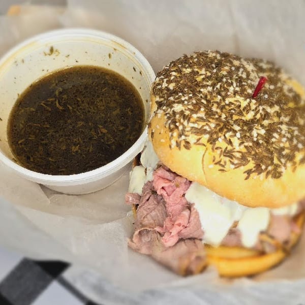 Main St. Deli's roast beef sandwich with melted cheese and a side of au jus.